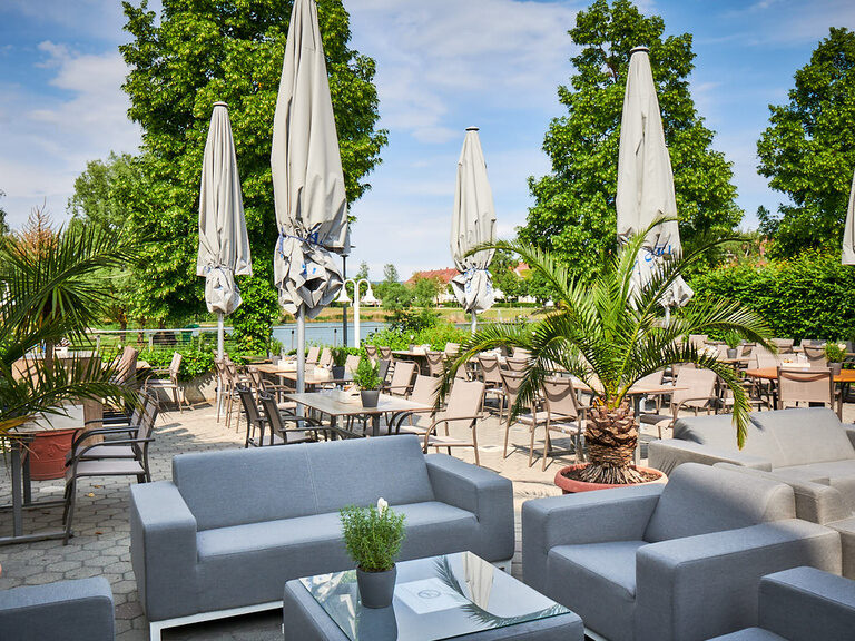 Auf der Terrasse des Hotels am See stehen einige Gartenmöbel
